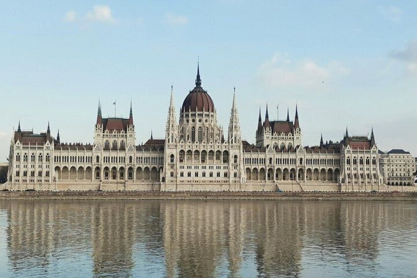 Un grand bâtiment imposant, richement décoré, doté d’un dôme central et de nombreuses flèches, qui se reflète dans les eaux calmes d’un plan d’eau. 4