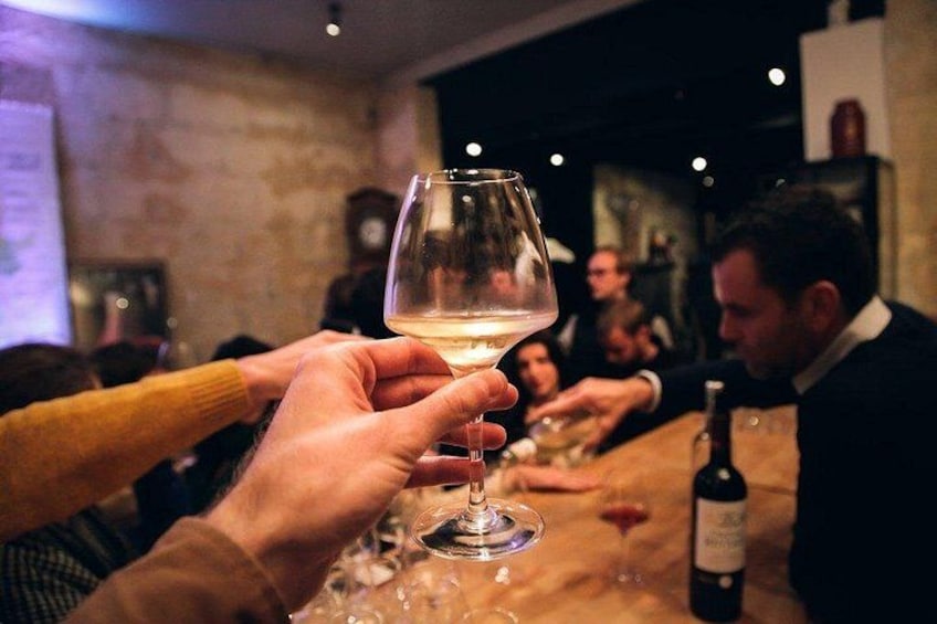A group of people toasting with wine glasses in a dimly lit bar. 4