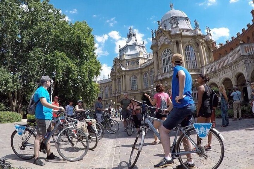Personas andando en bicicleta en una plaza con un edificio histórico al fondo. 3