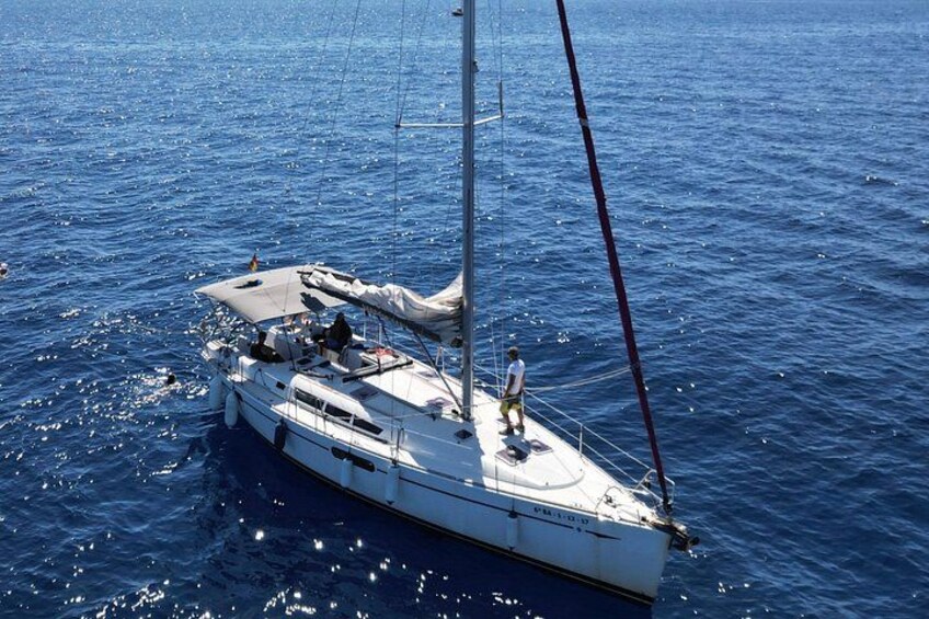 Un velero con mástil y velas en aguas azules tranquilas. 4