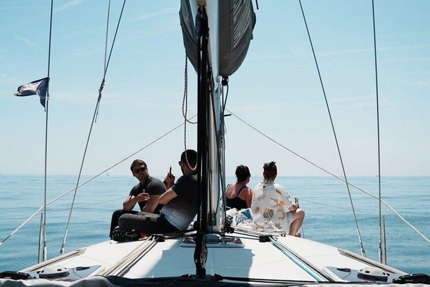 Un velero con cuatro personas a bordo, cielo despejado y mar en calma. 3