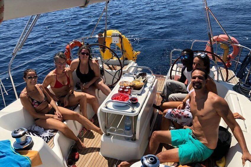 A boat with people sitting on the deck, a steering wheel, and a life preserver. 2