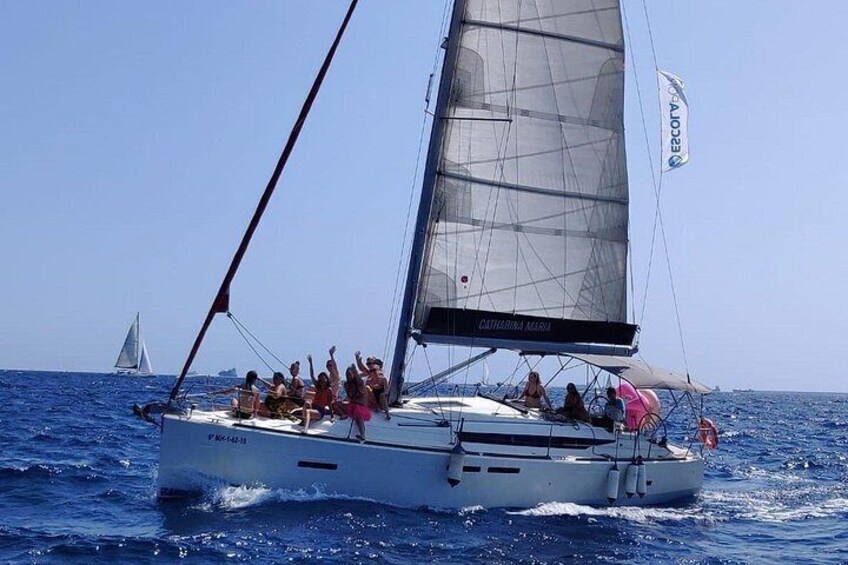 A sailboat with passengers on the water, a clear sky, and another sailboat in the distance. 3