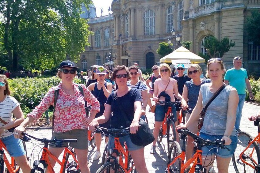 En gruppe mennesker på cykler foran en stor, historisk bygning. 4