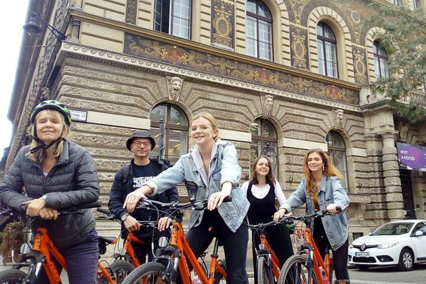 Eine Gruppe von Radfahrern vor einem historischen Gebäude mit aufwendiger Architektur. 3