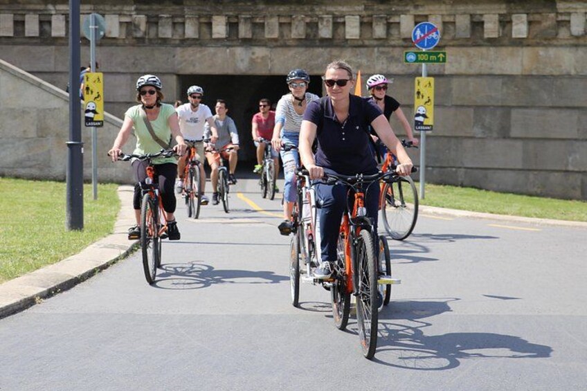 En gruppe cyklister på en asfalteret vej med en tunneltilgang i baggrunden. 3