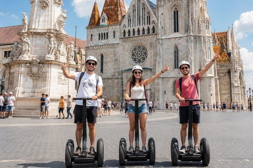 Tres personas en segways frente a una catedral con estatuas y un gran ventanal circular. 1