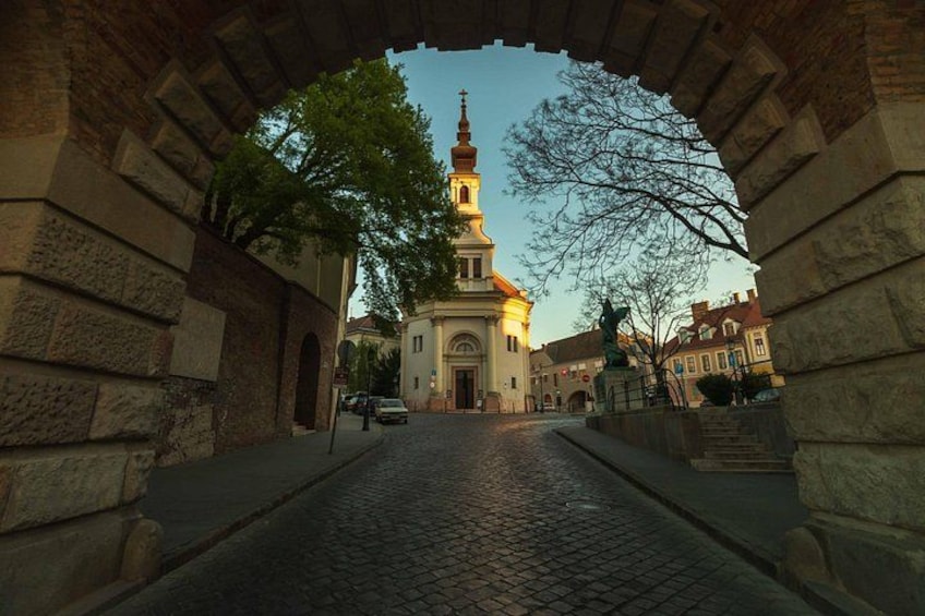 Una strada acciottolata che conduce a una chiesa con un campanile alto. 2