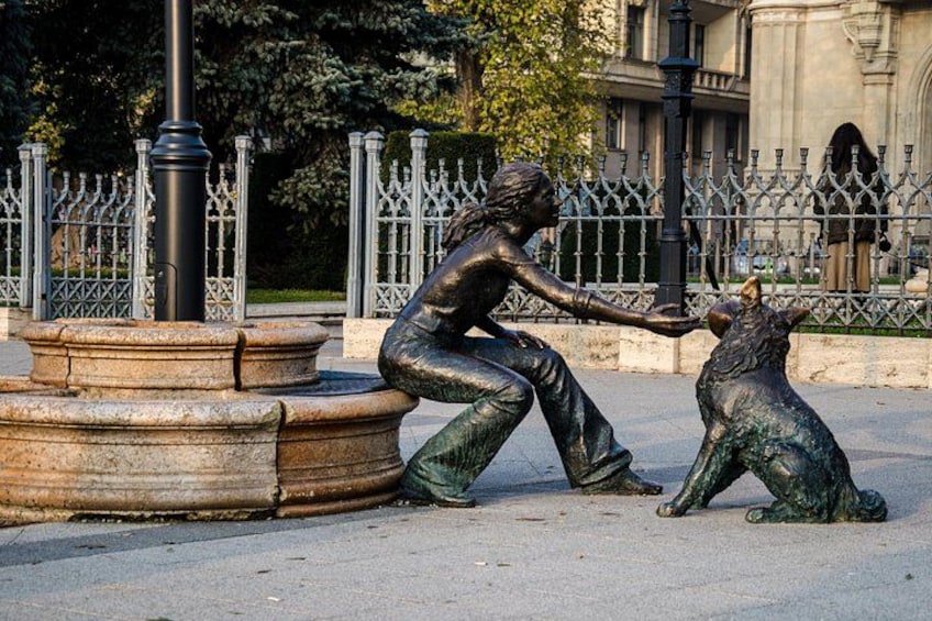 A bronze statue of a woman and a bear in a park. 3