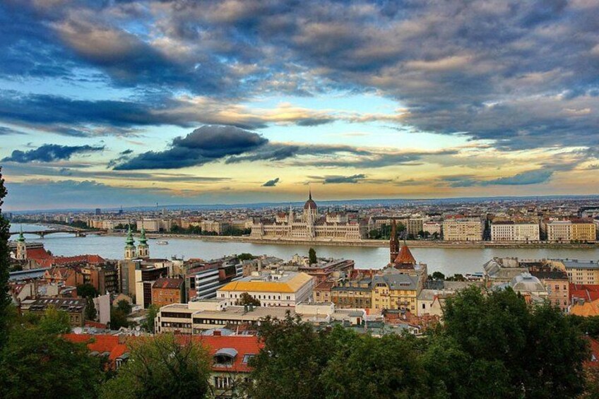 A cityscape with a river, historic buildings, and a prominent church with a green roof. 1