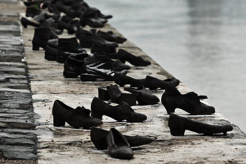 A row of shoes lined up on a concrete ledge by a body of water. 4