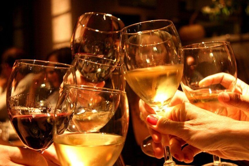 Multiple wine glasses filled with white wine, held by hands. 1