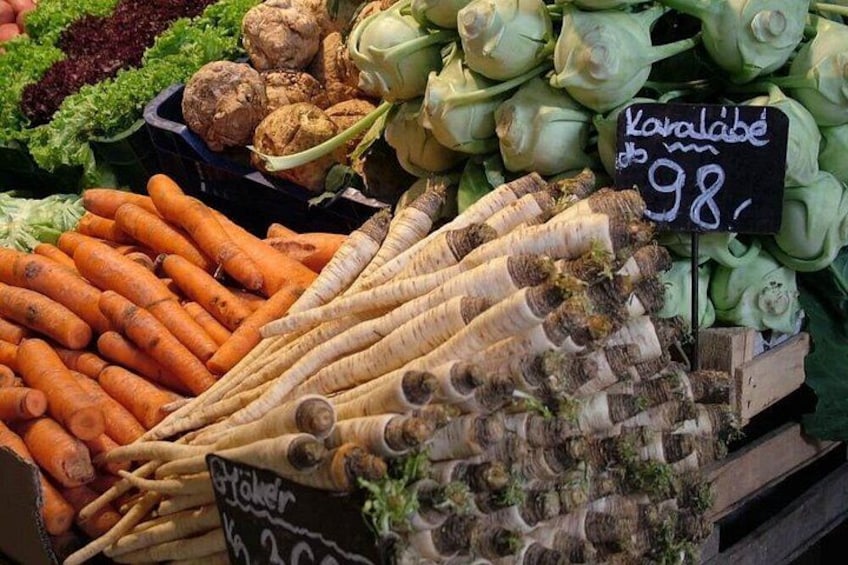 Un puesto de mercado con verduras frescas, incluyendo zanahorias, alcachofas y hinojo. 5