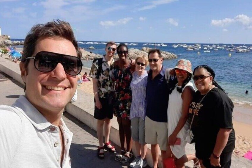 A group of people on a beach with boats in the background. 3