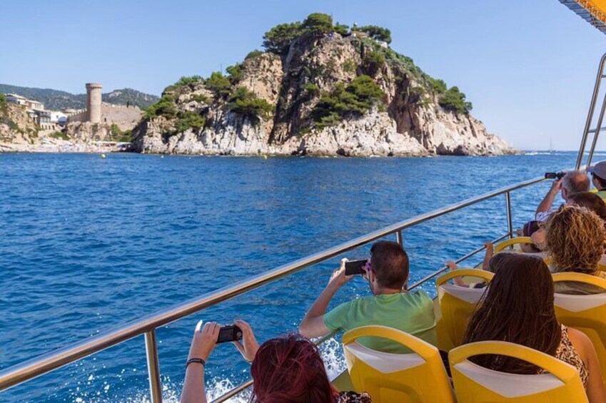 A boat with passengers taking photos of a rocky island in the distance. 4