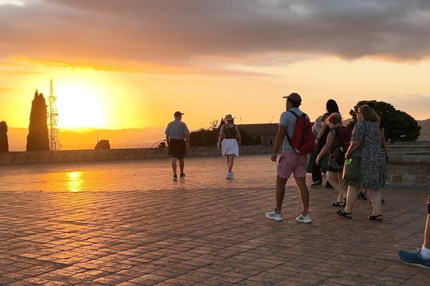 A sunset over a paved area with people walking. 3