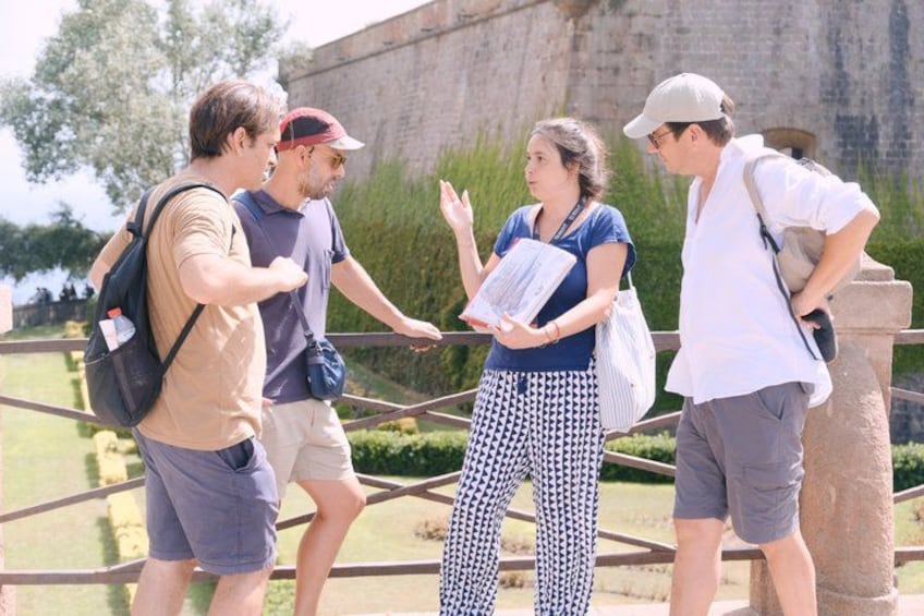 A group of people standing by a stone wall, one person holding a booklet. 4