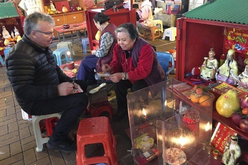 Three people sitting at a table with a glass display case containing fruits and a candle. 5
