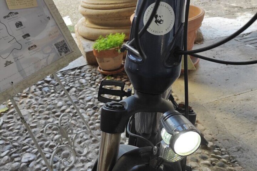 A motorcycle with a headlight, a map, and potted plants. 2