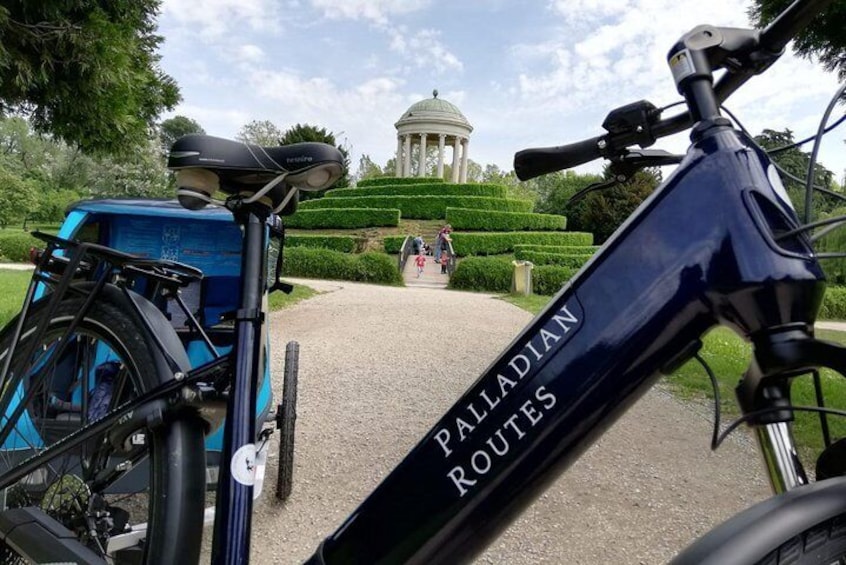 A bicycle with 'Palladian Routes' written on it, a blue car, and a gazebo in the background. 1