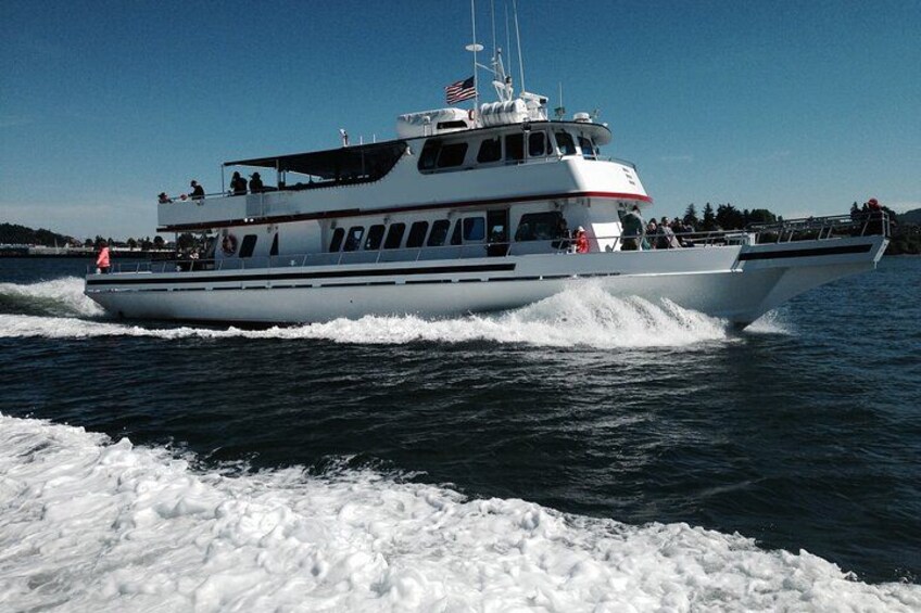 A white boat with multiple decks and passengers, moving through a body of water. 2