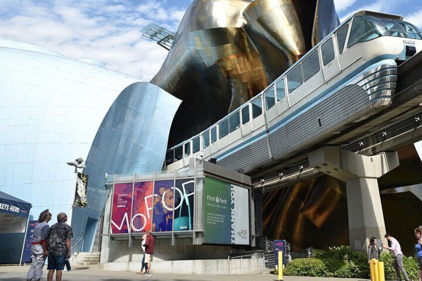 A futuristic building with a metallic structure and a train on an elevated track. 2