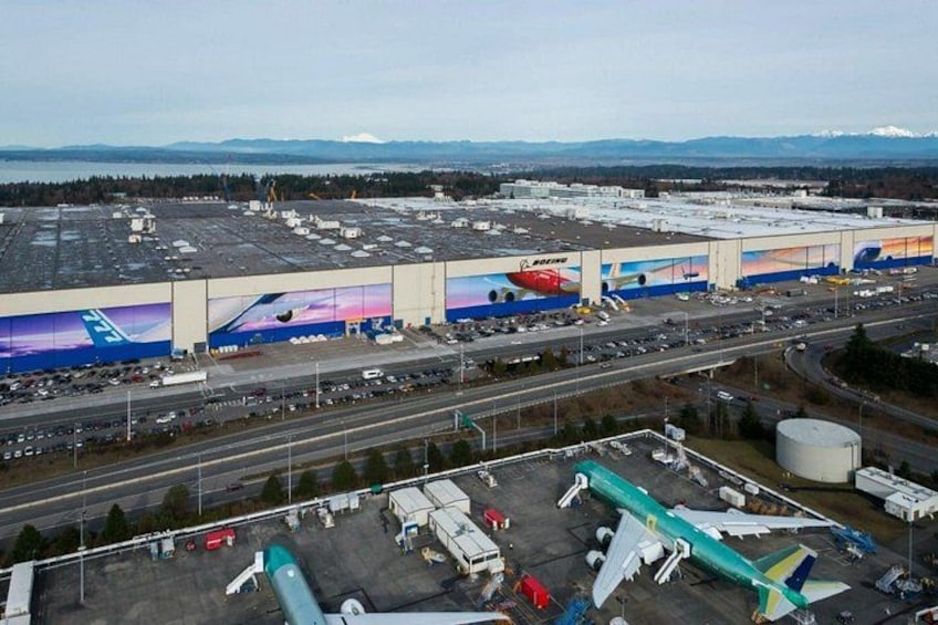 Un aeropuerto con un hangar grande, aviones estacionados y un paisaje montañoso al fondo. 2