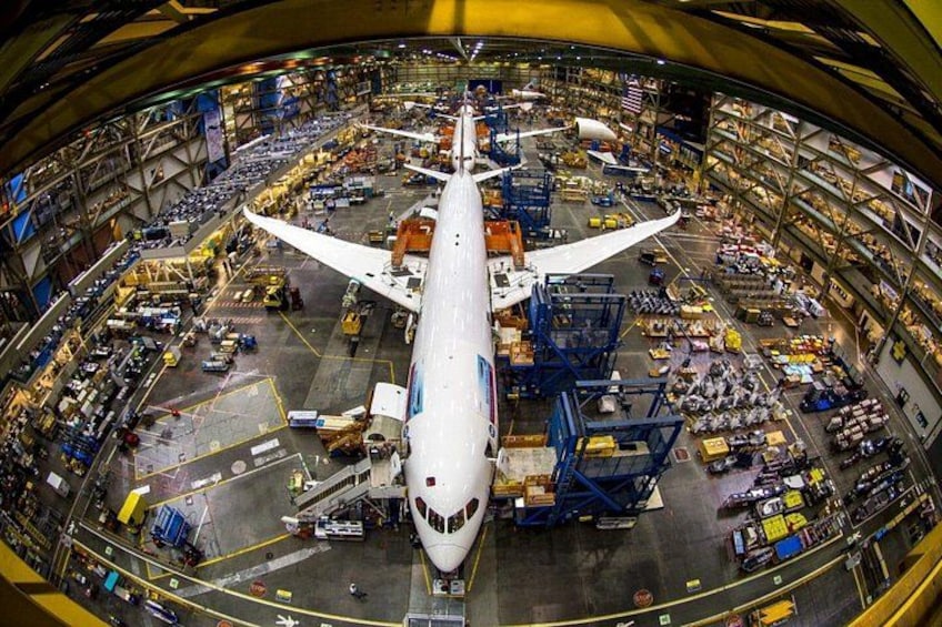Un grand avion se trouve dans un hangar, entouré de divers équipements et véhicules. 5