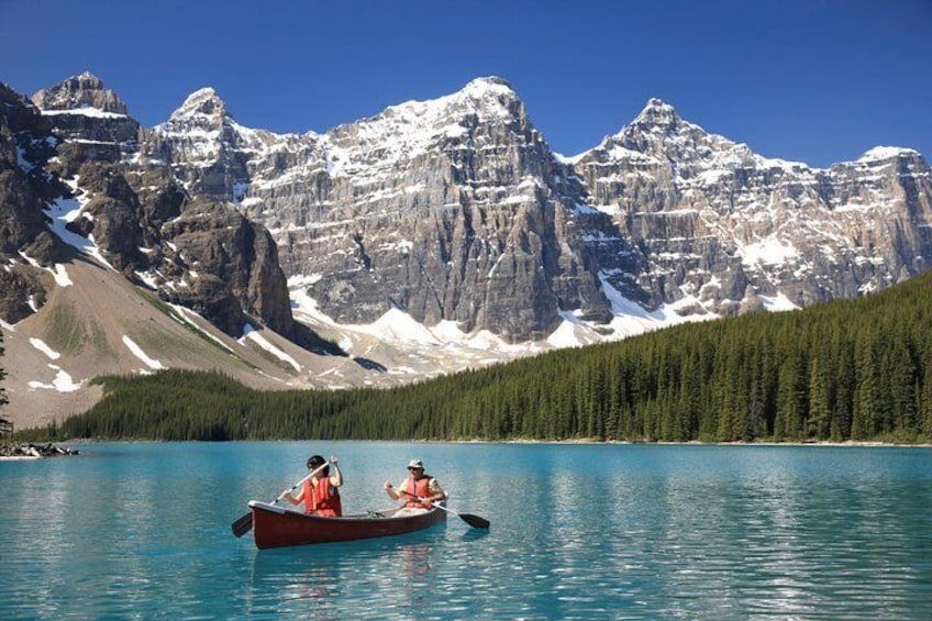 Two people in a canoe on a lake with mountains in the background. 2