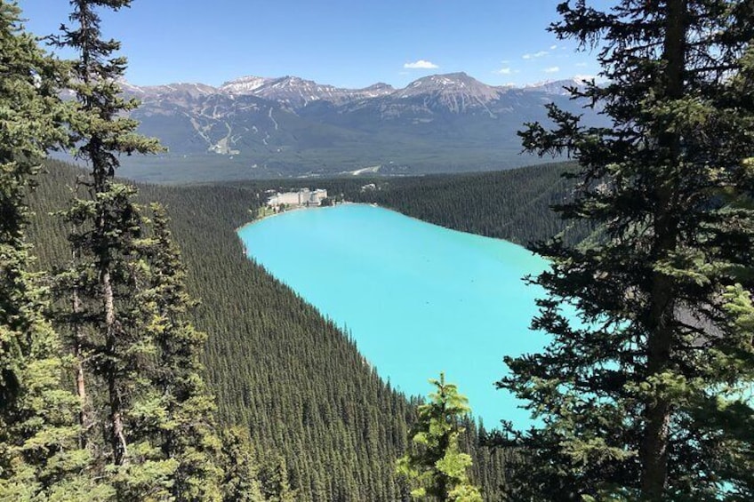 A turquoise lake surrounded by dense forest and mountains. 4