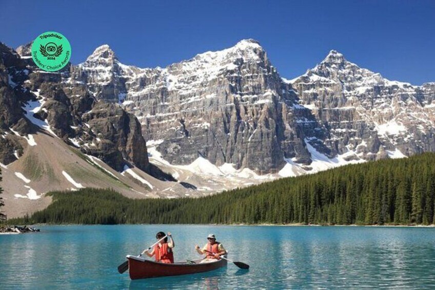 A lake with two people in a canoe surrounded by mountains and forest. 1