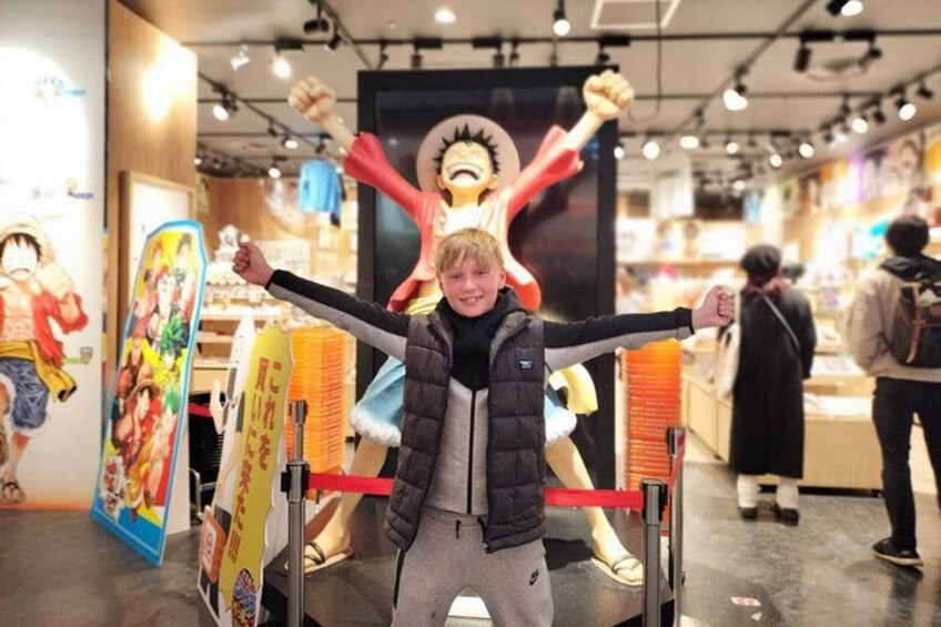Un enfant se tient devant une grande affiche représentant un personnage, entouré de produits dérivés. 3