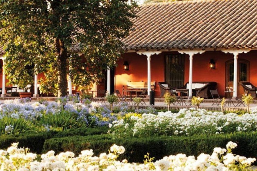 A traditional building with a tiled roof, surrounded by a well-maintained garden with white flowers and trimmed hedges. 4