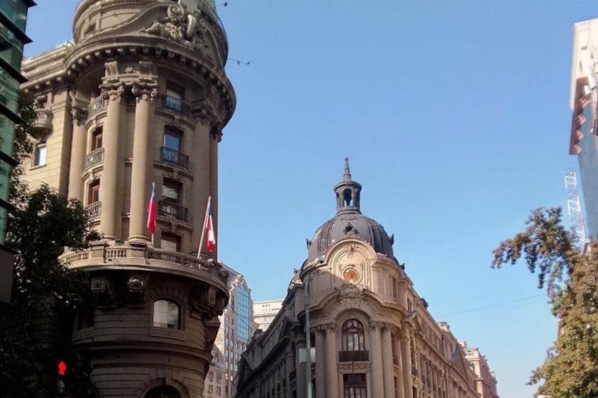 Un edificio histórico con una cúpula y columnas, banderas y un cielo azul despejado. 4