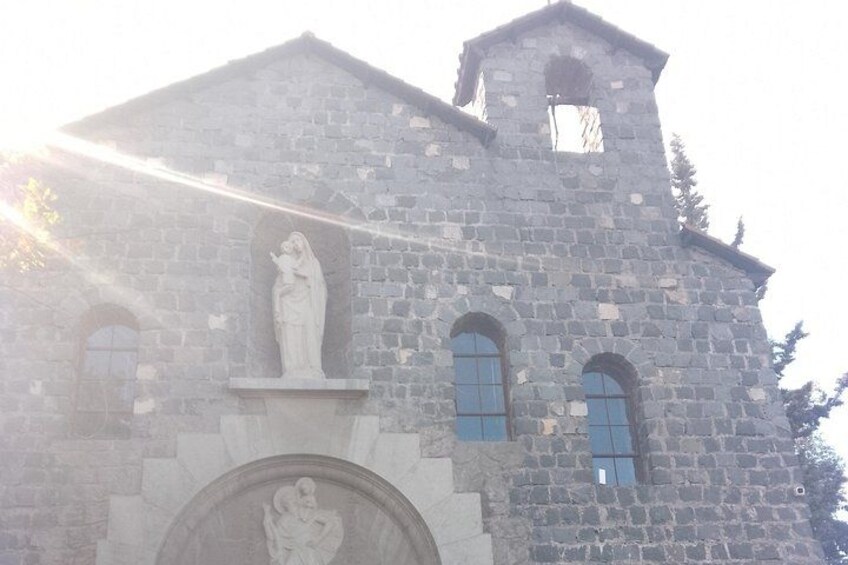 Una iglesia de piedra con una torre de campanas, ventanas en arco y una estatua en la fachada. 2
