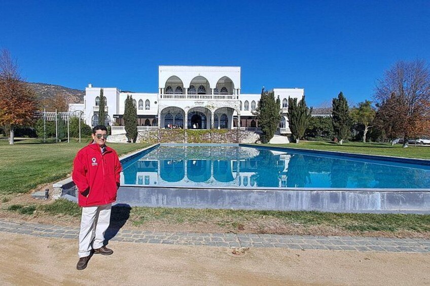 A person standing in front of a large pool with a building in the background. 4