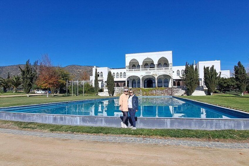 A swimming pool, a large white building with arches, and a clear blue sky. 5