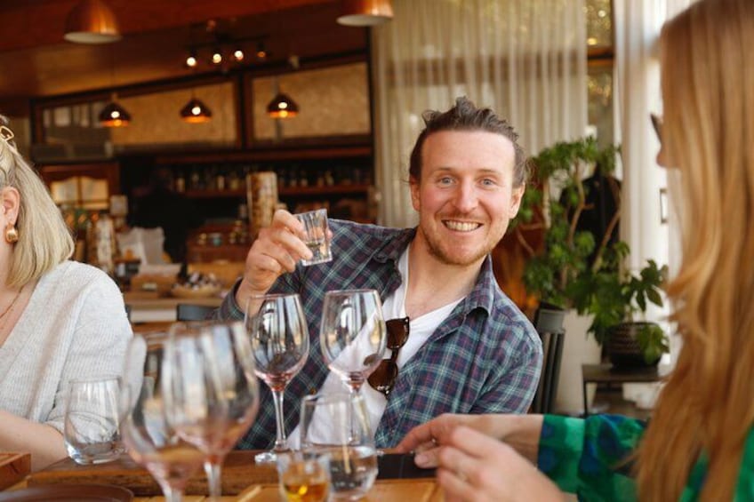 A person holding a glass of wine at a table with other glasses. 3