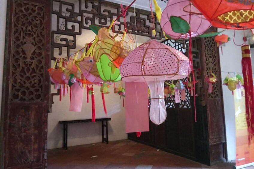 Ein Zimmer mit hängenden dekorativen Sonnenschirmen und einem traditionellen Holzziergitter. 5