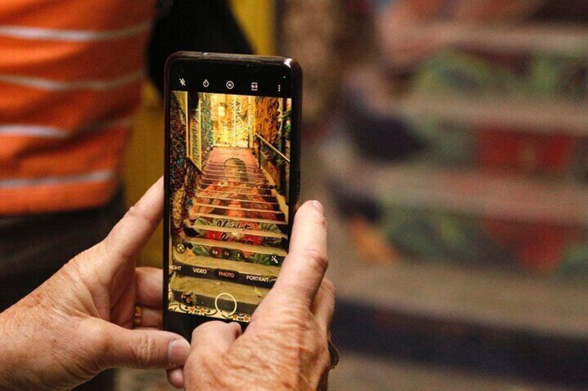 A person holding a smartphone displaying a photo of a staircase. 2
