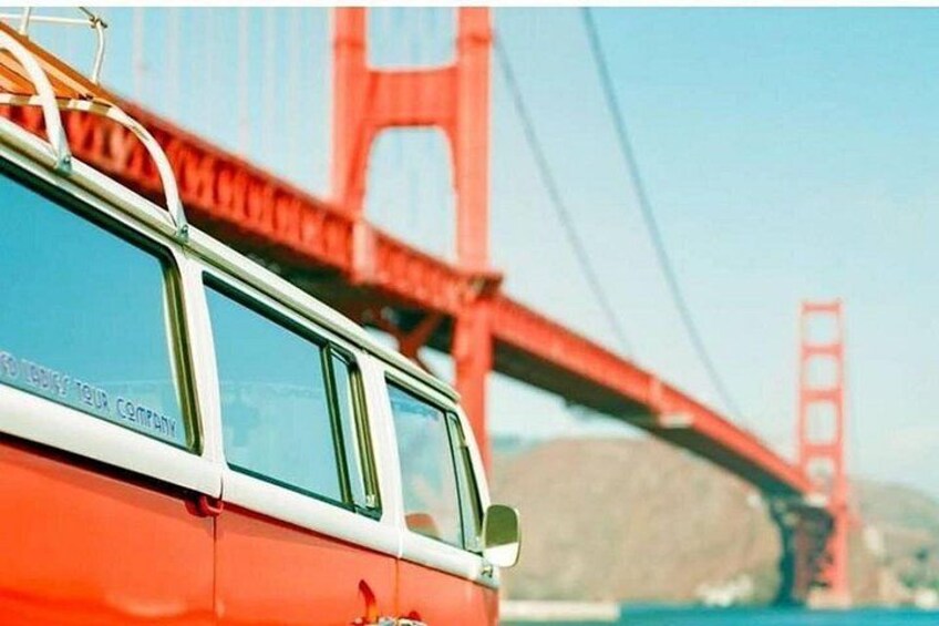 Een rode auto met een wit dak geparkeerd voor de Golden Gate Bridge. 2