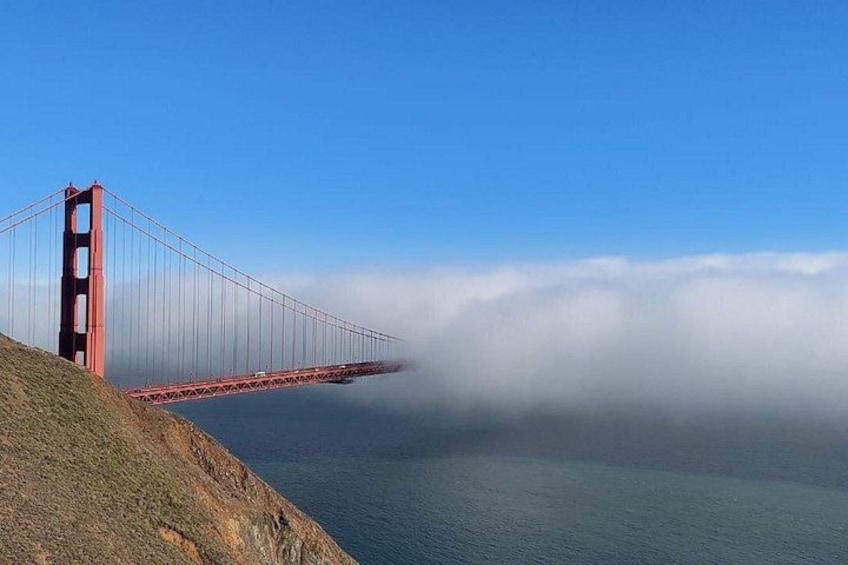 A red bridge spanning a body of water, with fog near the base of the bridge. 3