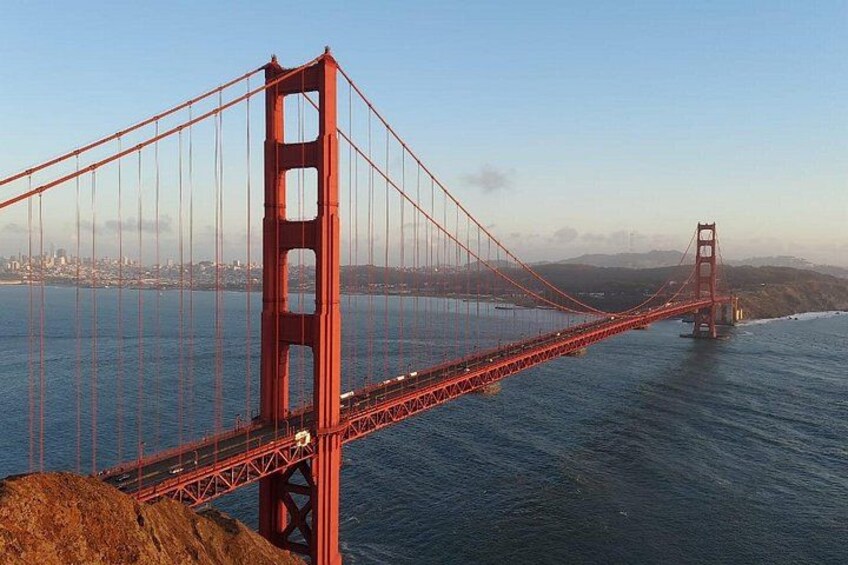 A suspension bridge spanning a body of water with a city skyline in the background. 3