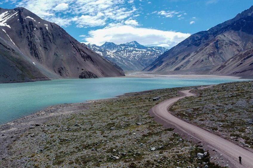 A winding mountain road, a turquoise lake, and snow-capped peaks. 1