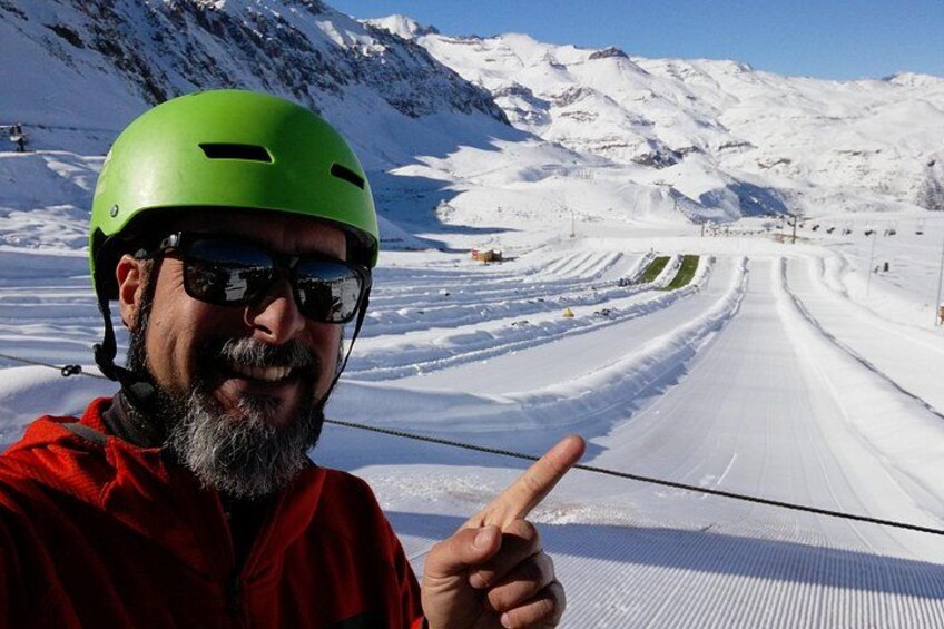 A person in a red jacket pointing at a snow-covered road with mountains in the background. 5