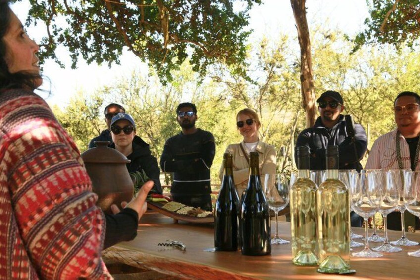 A group of people at an outdoor event with wine bottles and glasses on a table. 3