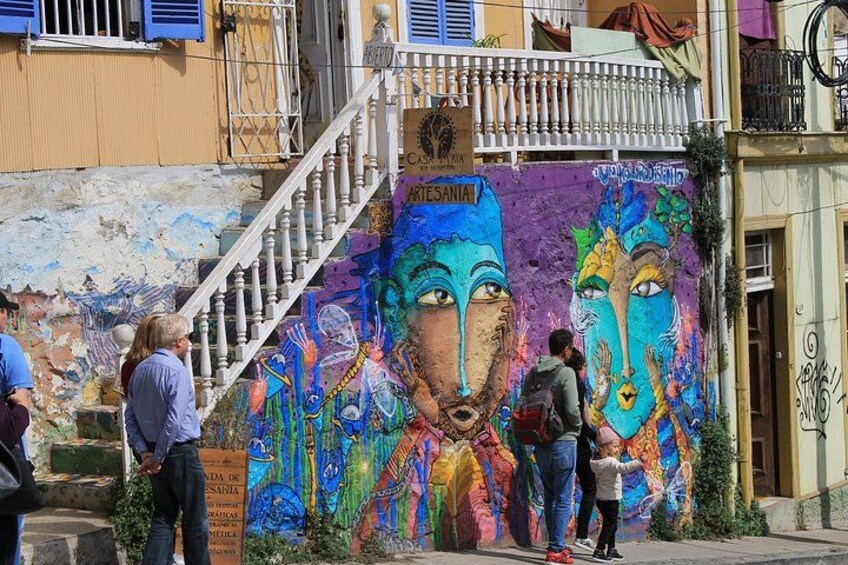 Une fresque colorée orne le mur d’un immeuble, et un escalier y mène à un balcon. 2