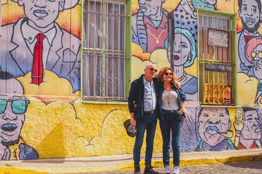 A mural with colorful faces and a building with barred windows. 4