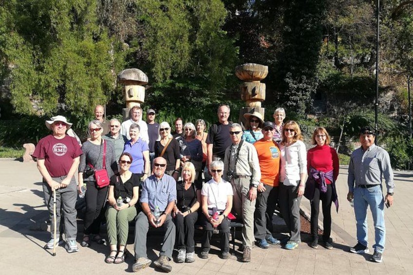 A group of people posing in an outdoor setting with trees and stone structures in the background. 4