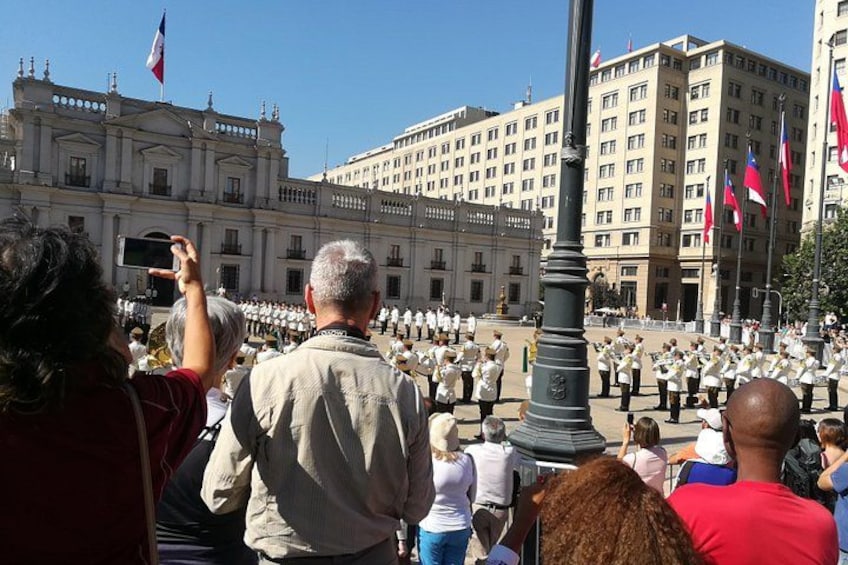 A formal ceremony with uniformed personnel in a public square, surrounded by historic buildings and flags. 3